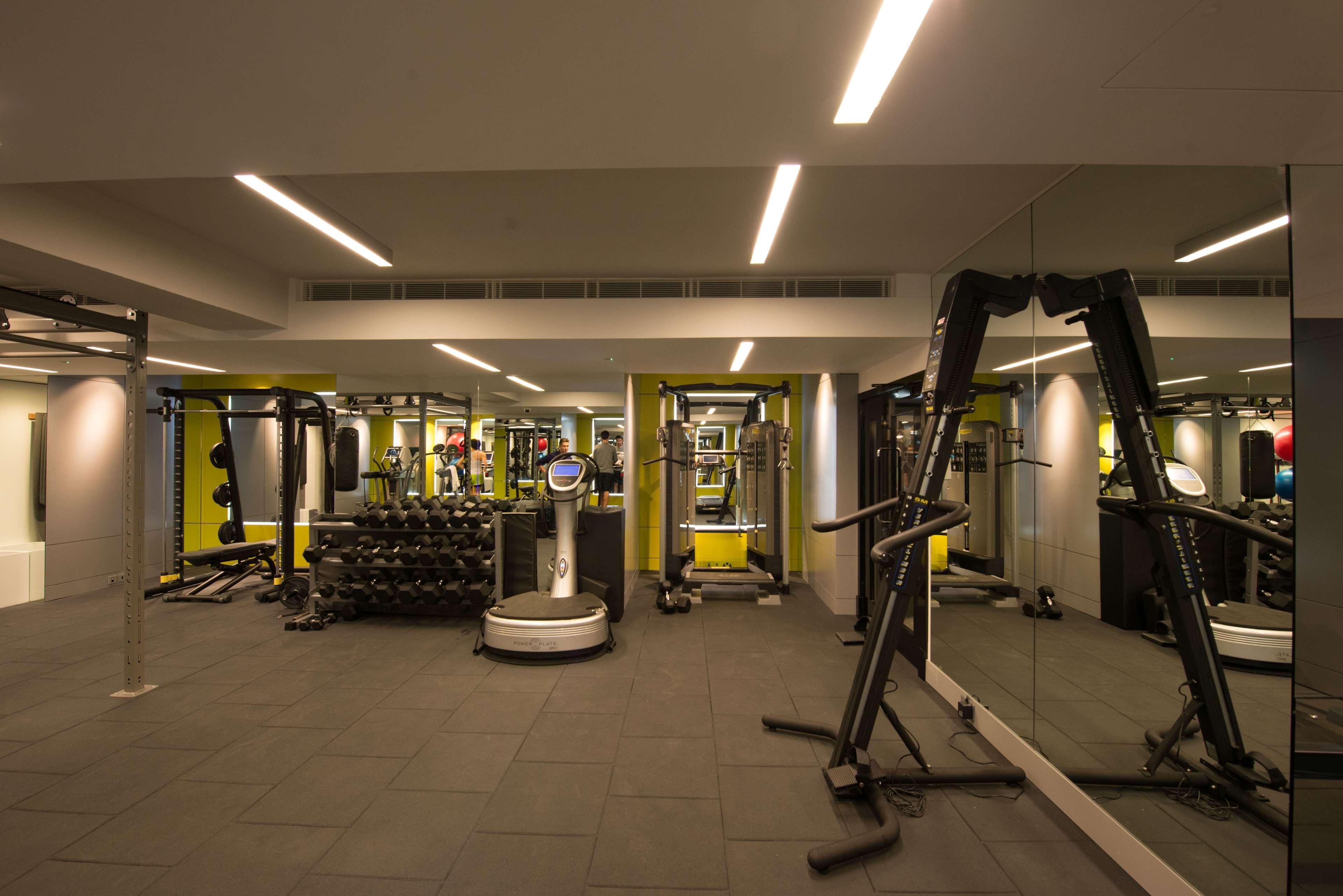 The May Fair, A Radisson Collection Hotel, Mayfair London Exterior photo The photo shows the interior of a gym. It features various exercise equipment, including weight machines, free weights, and a multi-purpose fitness machine. The gym has a modern design with yellow and gray accents, and it is well-lit with overhead li