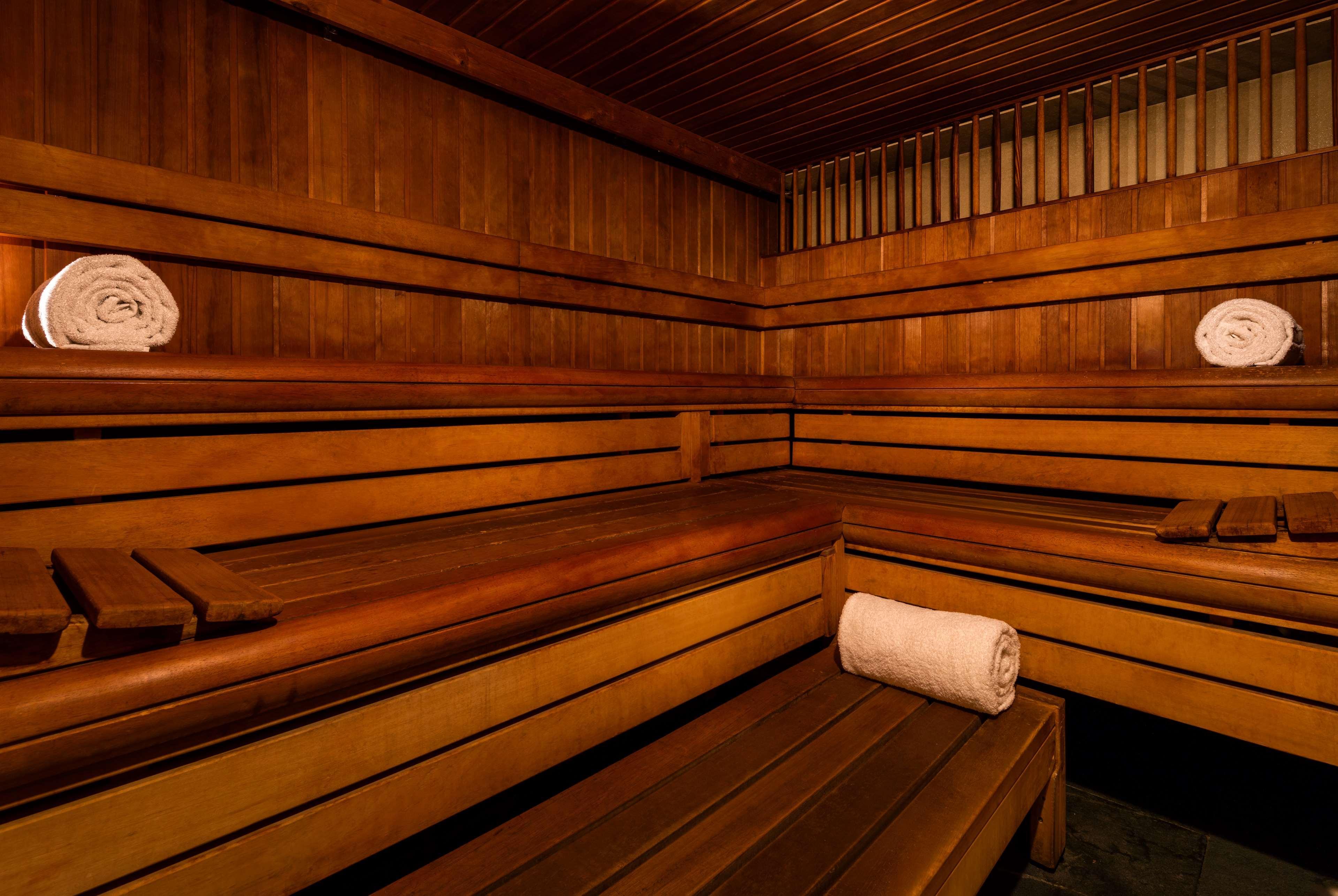 The May Fair, A Radisson Collection Hotel, Mayfair London Exterior photo The photo shows the interior of a sauna. It features wooden benches arranged along the walls, providing seating for visitors. There are neatly rolled white towels placed on the benches, giving a clean and inviting appearance. The walls and ceiling ar